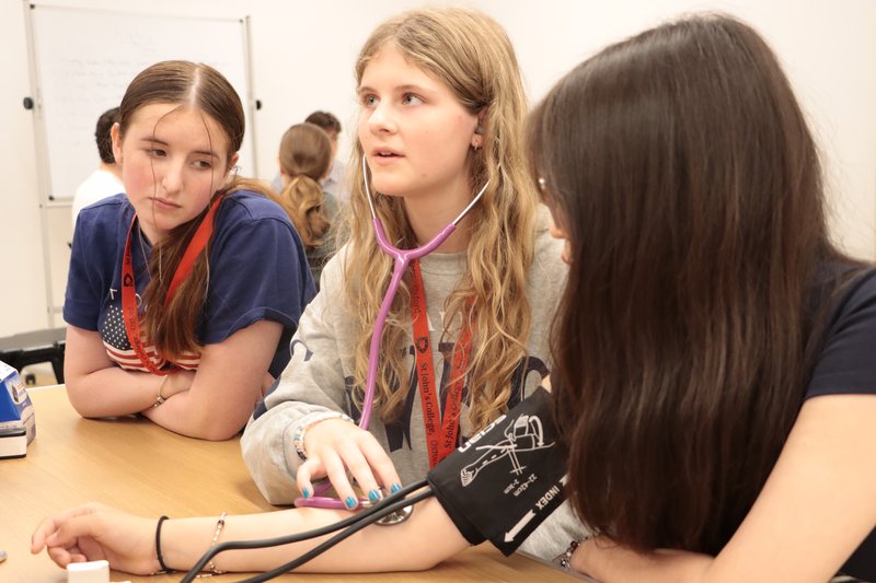 3 students in a Medicine workshop with stethoscope and blood pressure cuff